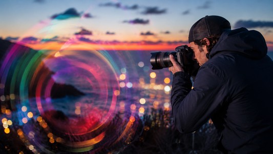 Photographer using creative camera movement to capture colorful light trails at twilight. 