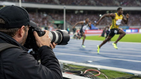 Sports photographer using a telephoto DSLR lens to capture sprinters racing on a stadium track